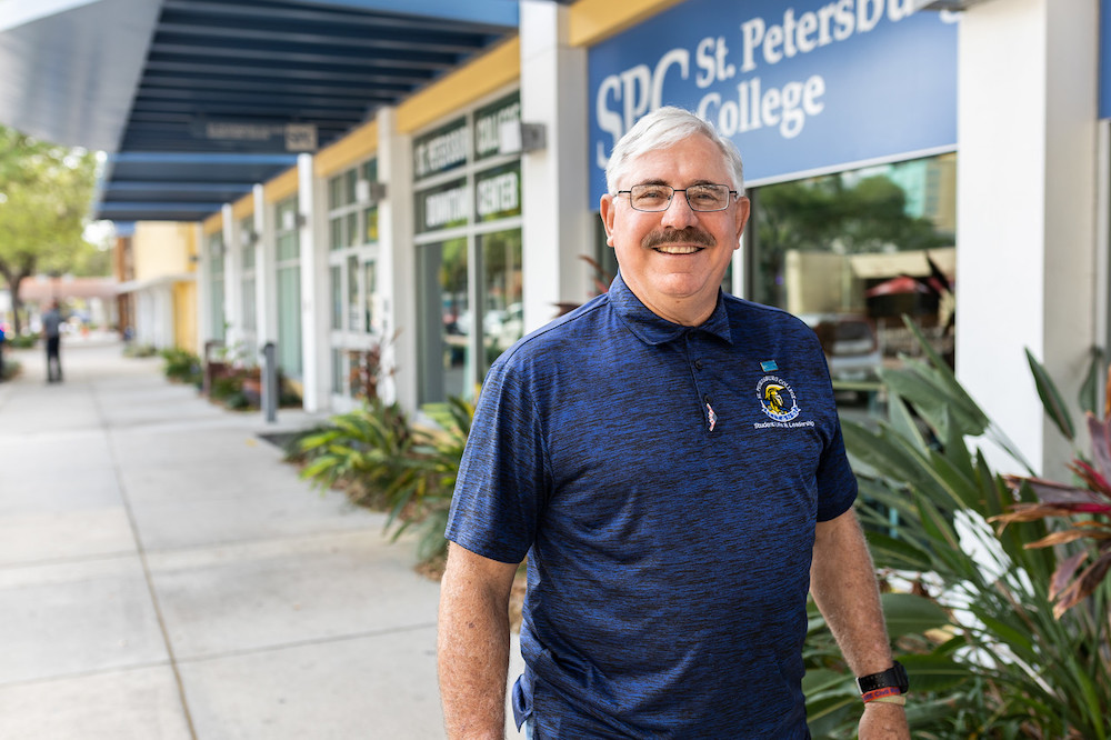 SPC student older male student in blue polo shirt walking in front of SPC's Downtown Center