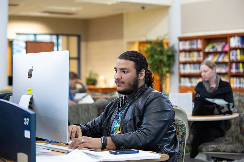 male student sitting at his computer getting it done