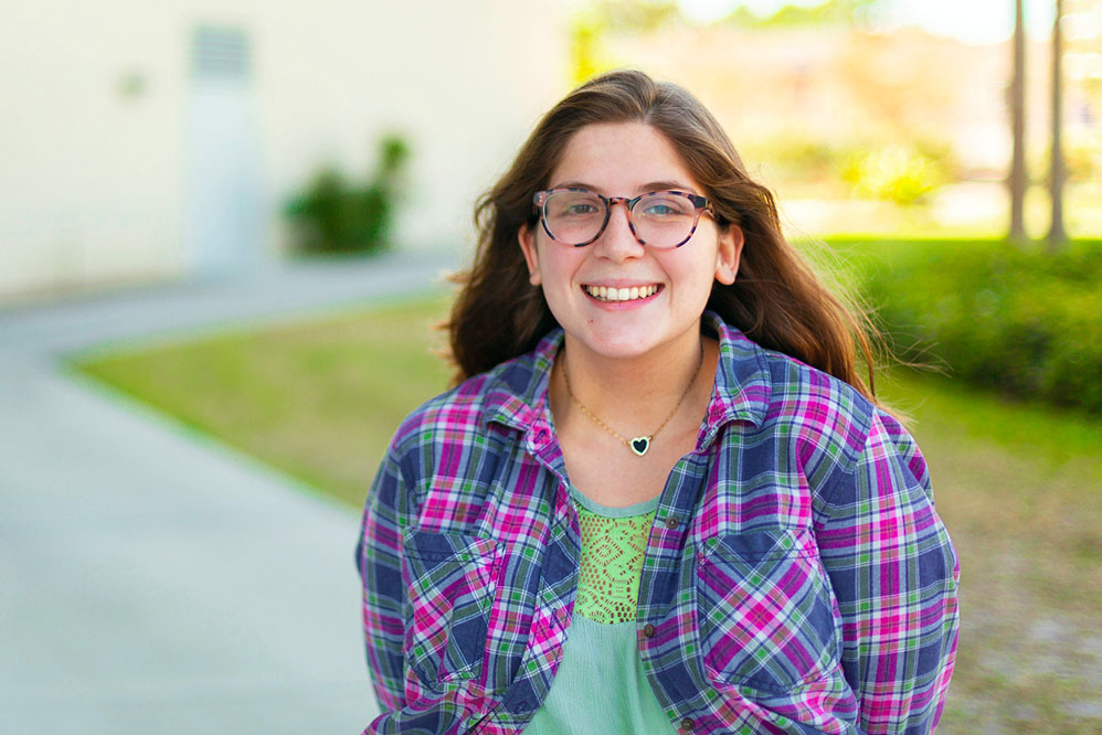 female SPC  student wearing glasses and a flannel shirt smiling