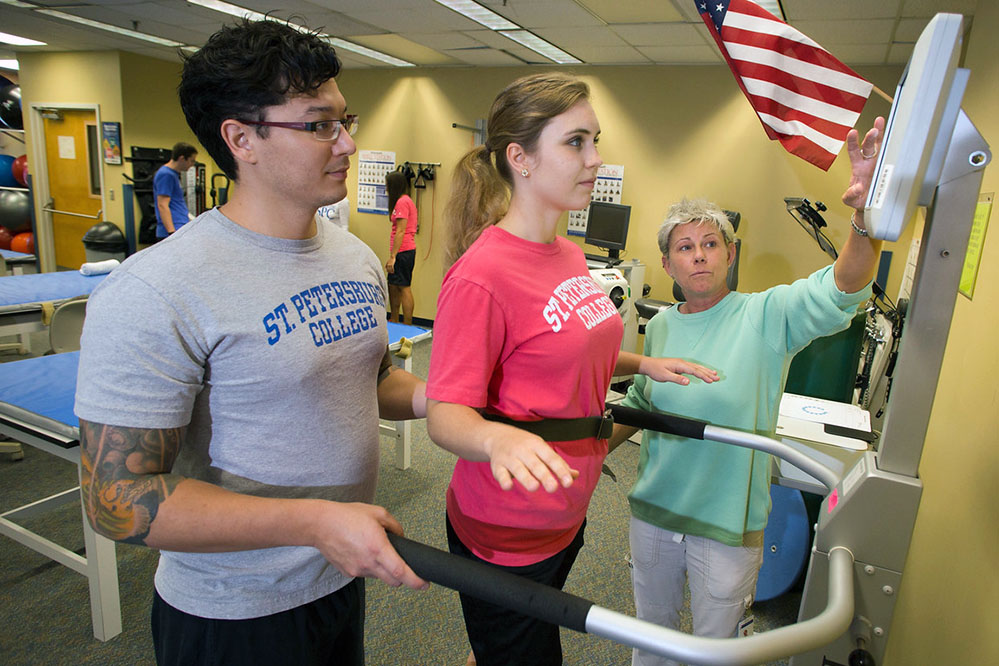 male and female student assisting a female student on a walking apparatus