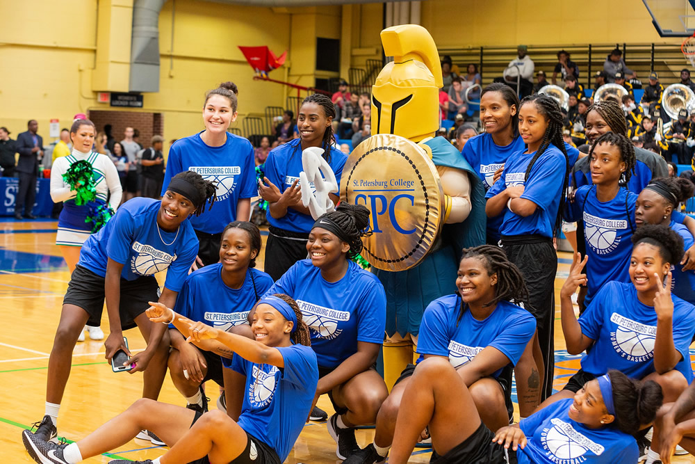 group of students sitting and standing at a basektball game posing with Titus, the Titan mascot