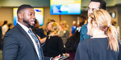 three individuals dressed in business attire  speaking at a conference