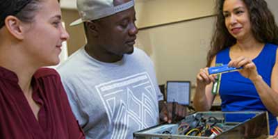 teacher demostrating a computer item to two students