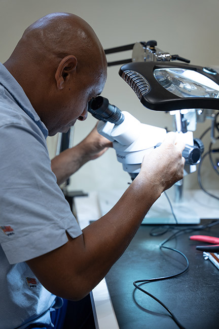 SPC graduate Derrick Snead demonstrates how to adjust the microscope in preparation to soldering a circuit card assembly