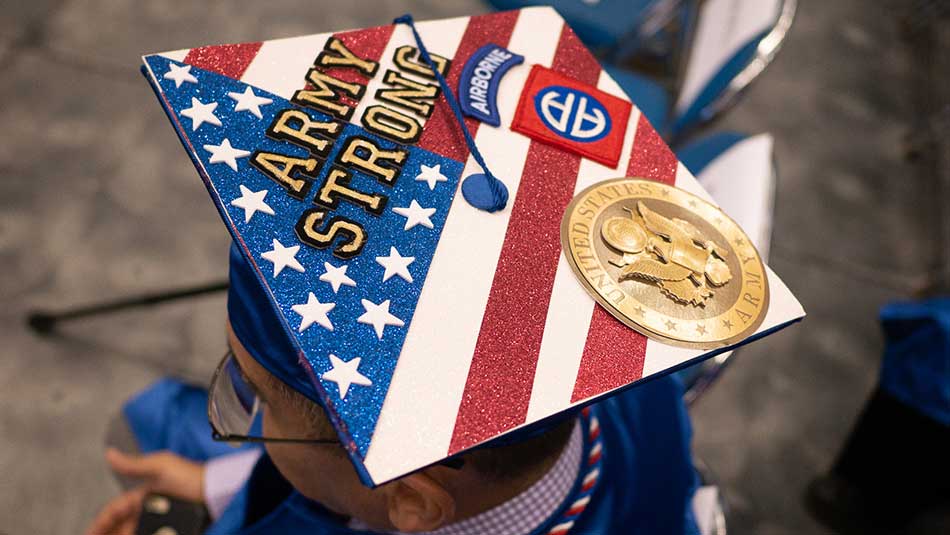 SPC graduate with vetarans memorabilia on top fo their graduation cap