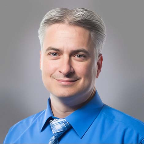 A portrait of Dr. Todd Van Auken, wearing a blue dress shirt and tie. 