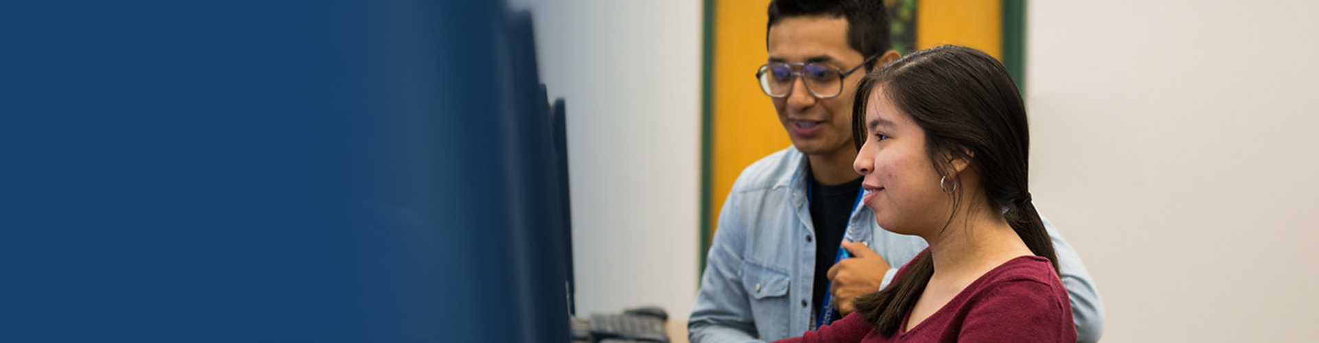 A student talking with an advisor at her desk.