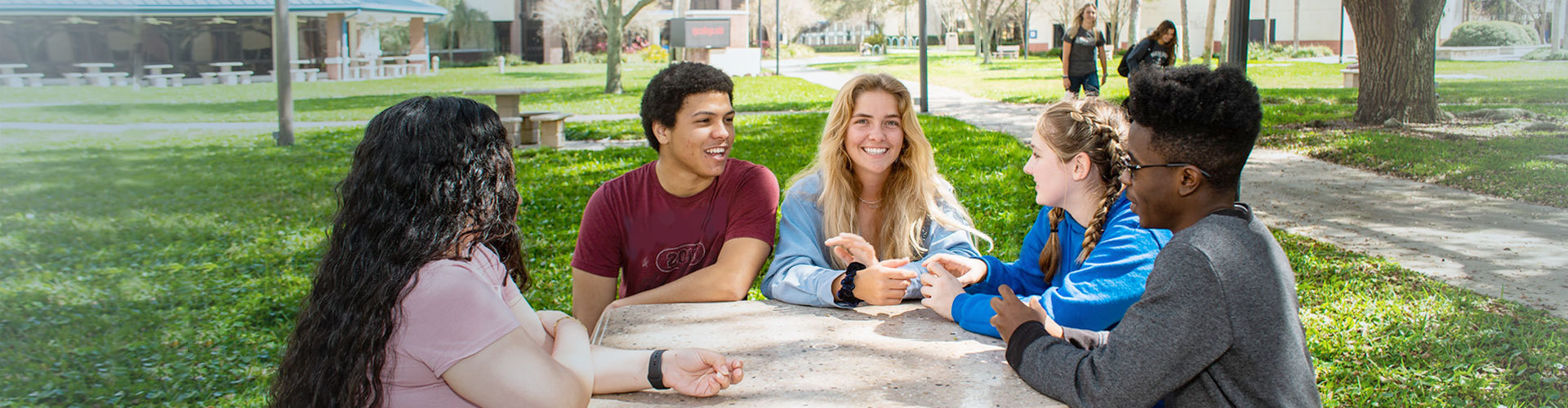 Mixed race students smiling while gathered at a round table