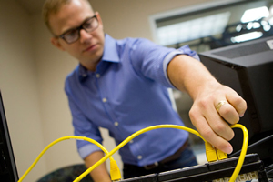 Man plugging in wires to a network switch.